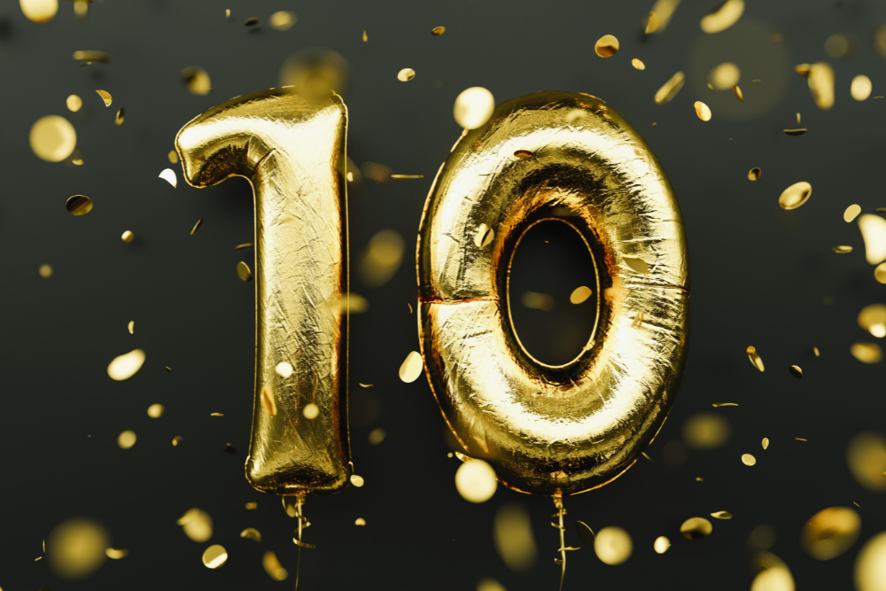 the number 10 in golden balloons with a black background and gold glitter and lights in the foreground